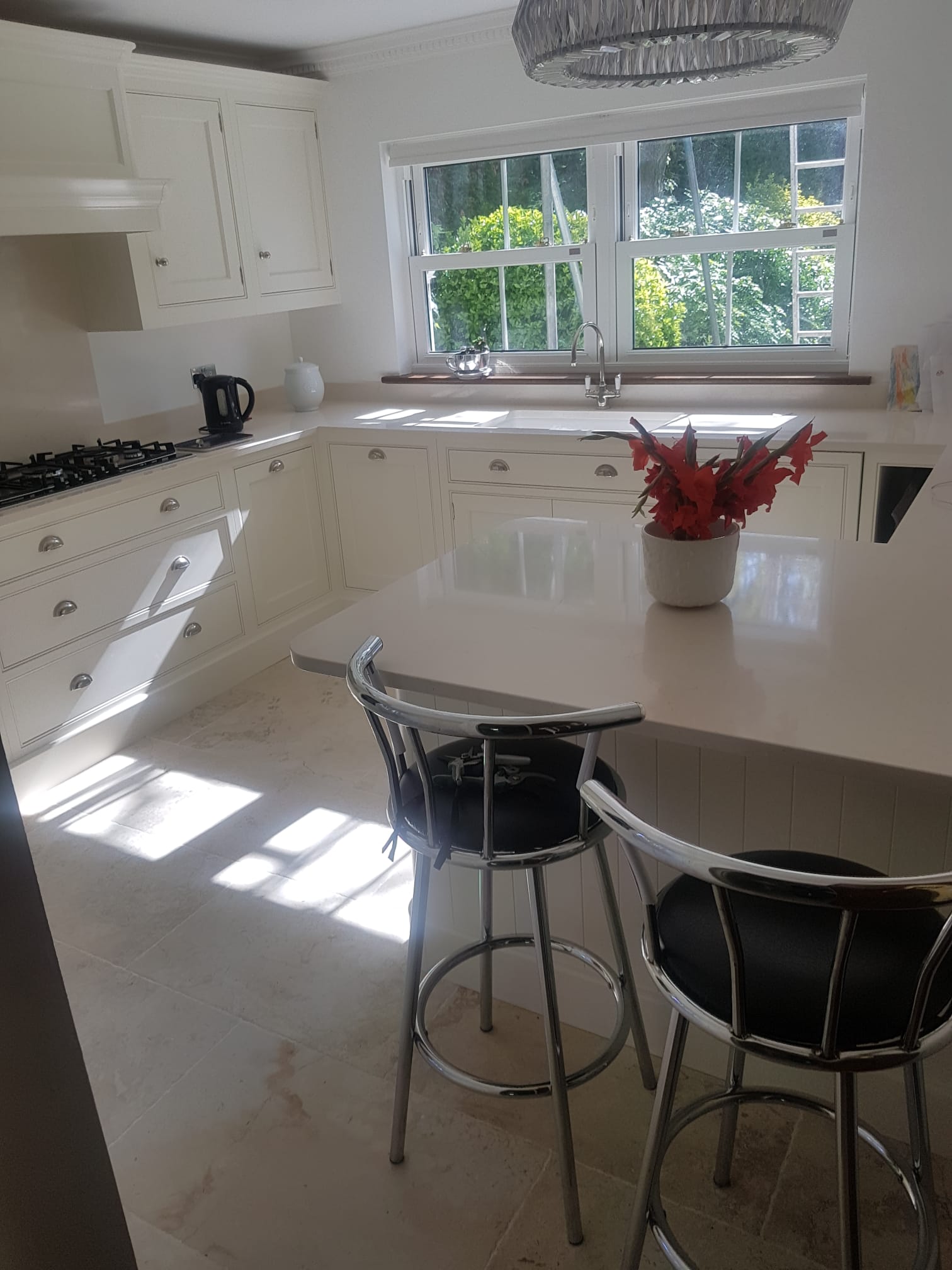 Finished bright fitted kitchen with island, white cabinetry and worktops
