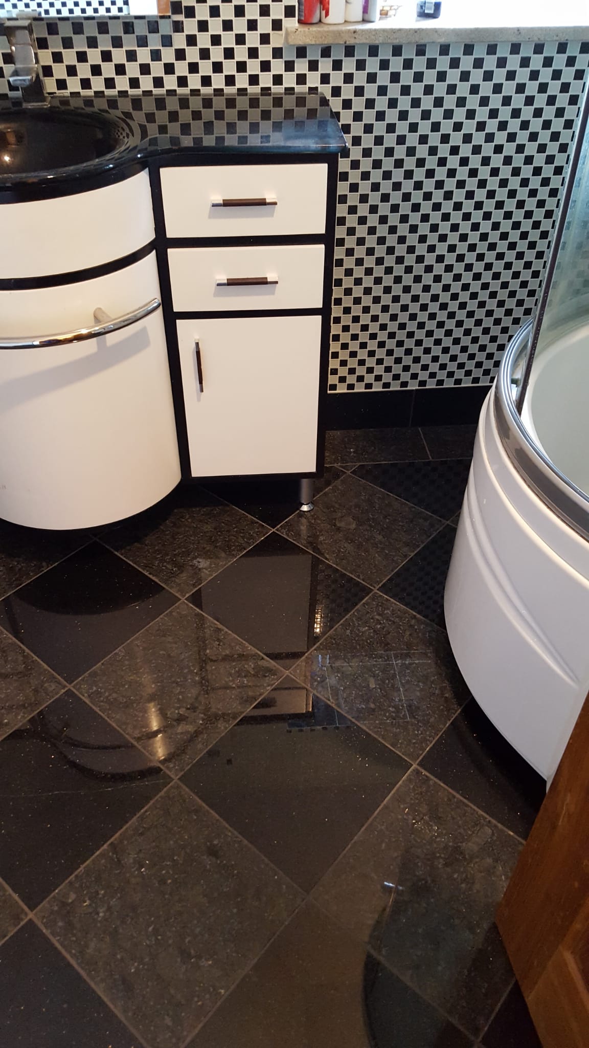 Bathroom vanity unit beside black and white mosaic wall tiling