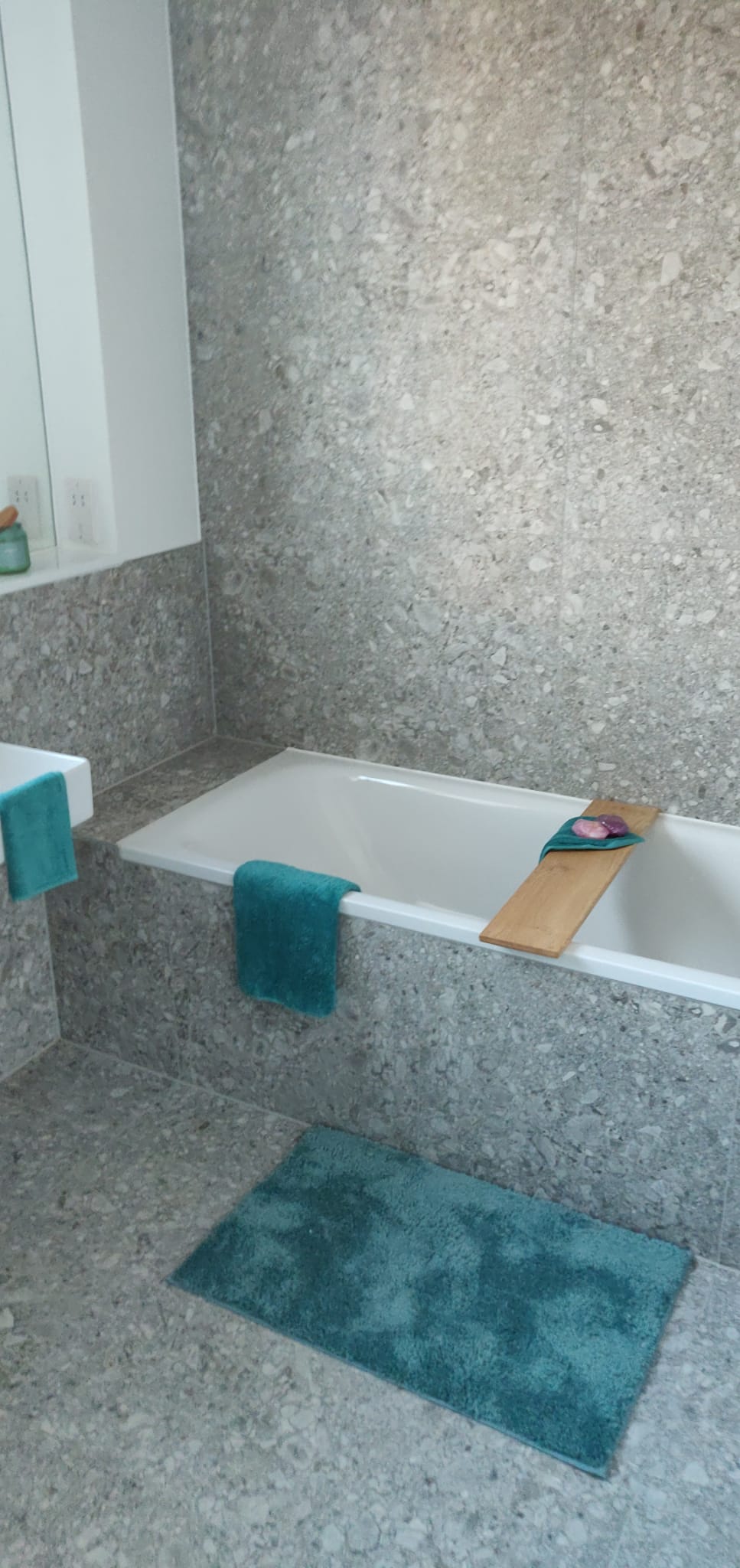 Finished stone-effect bathroom with fitted bath and teal accents