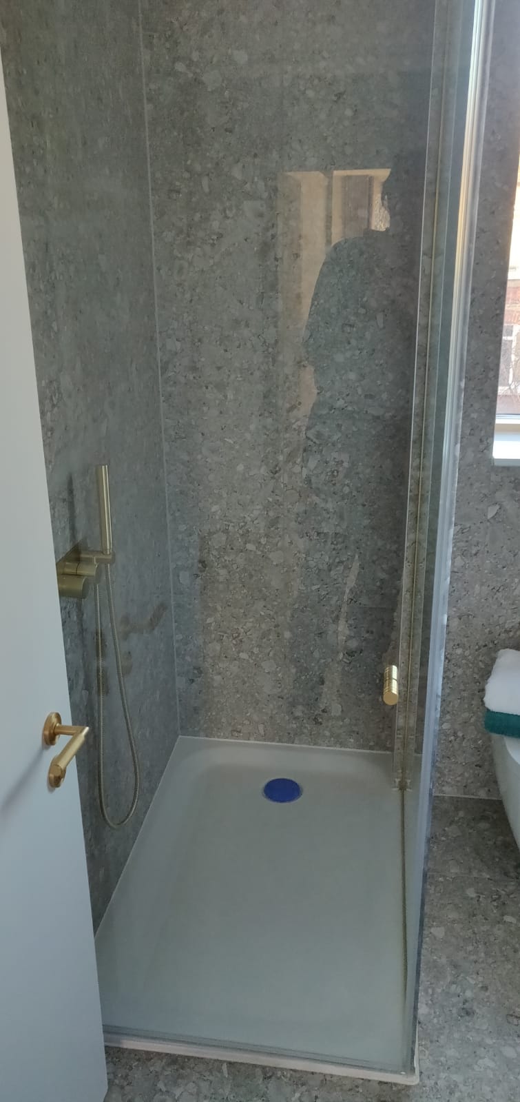 Finished walk-in shower with stone-effect wall tiles and brushed brass fittings